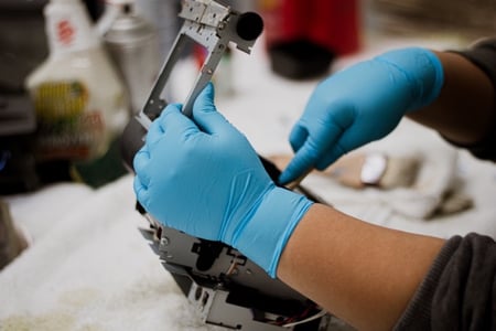 professional retail technology maintenance service technician wearing blue gloves cleaning and repairing point of sale hardware