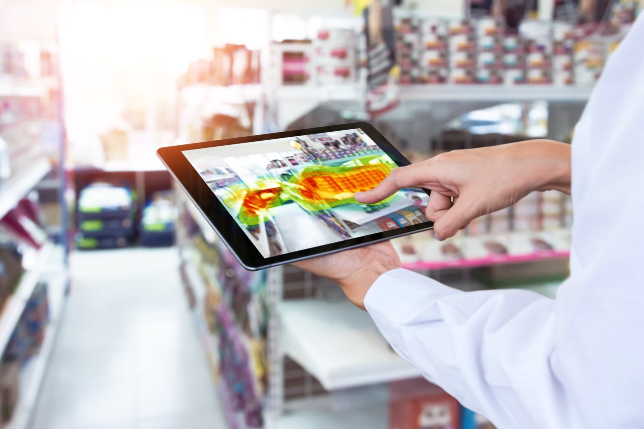 person's hands holding a tablet with a retail technology heatmap on tablet screen in retail store to identify shopper tendencies